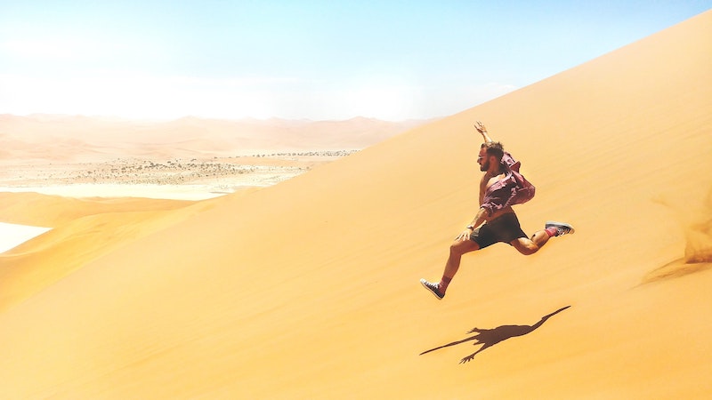 man running down side of sand dune