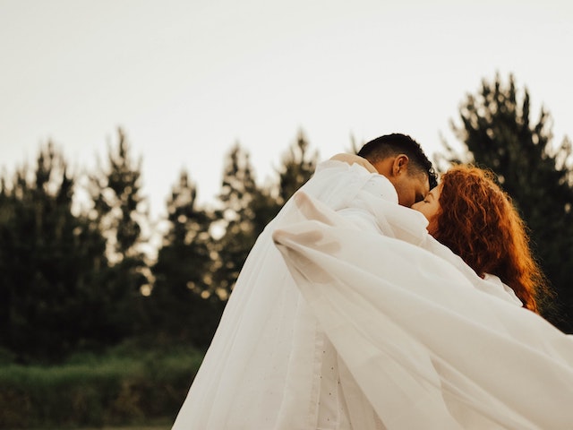 man and woman kissing under sheet