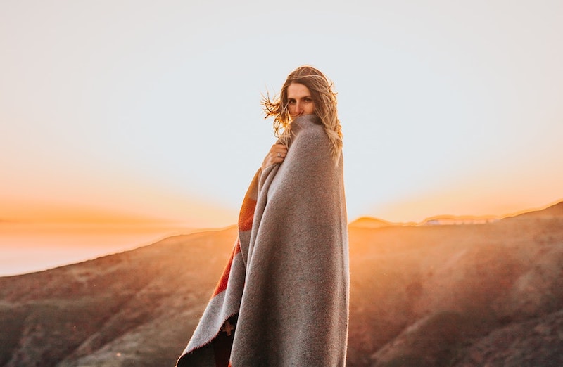 woman in blanket with sunset behind