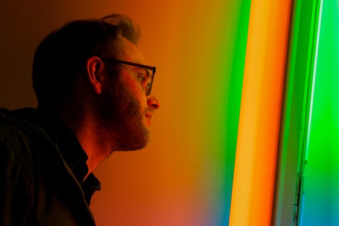 bearded man standing in front of color light