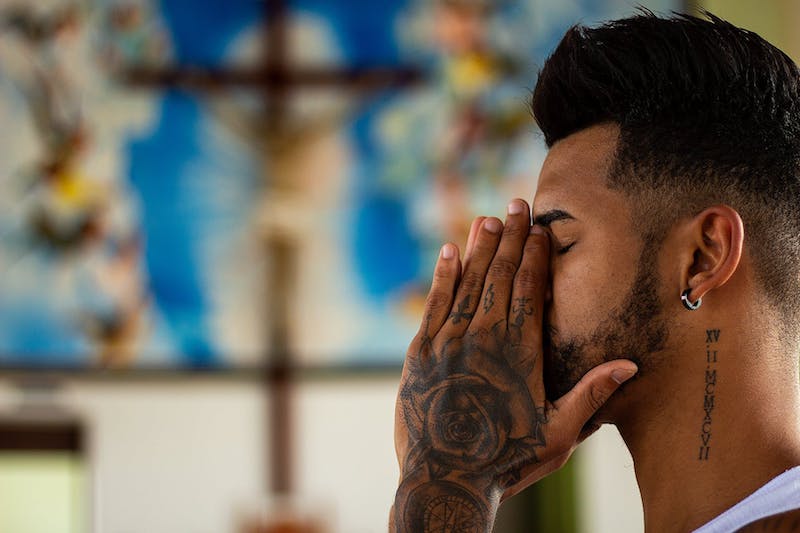 man with tattoos praying