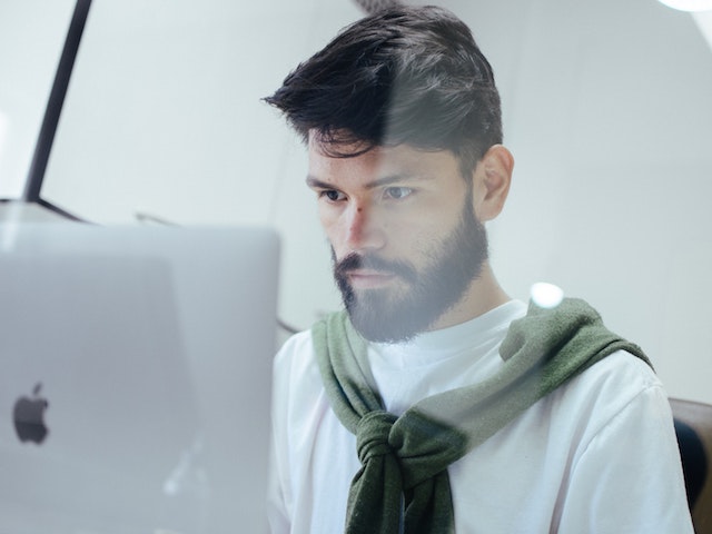 bearded man looking at computer screen